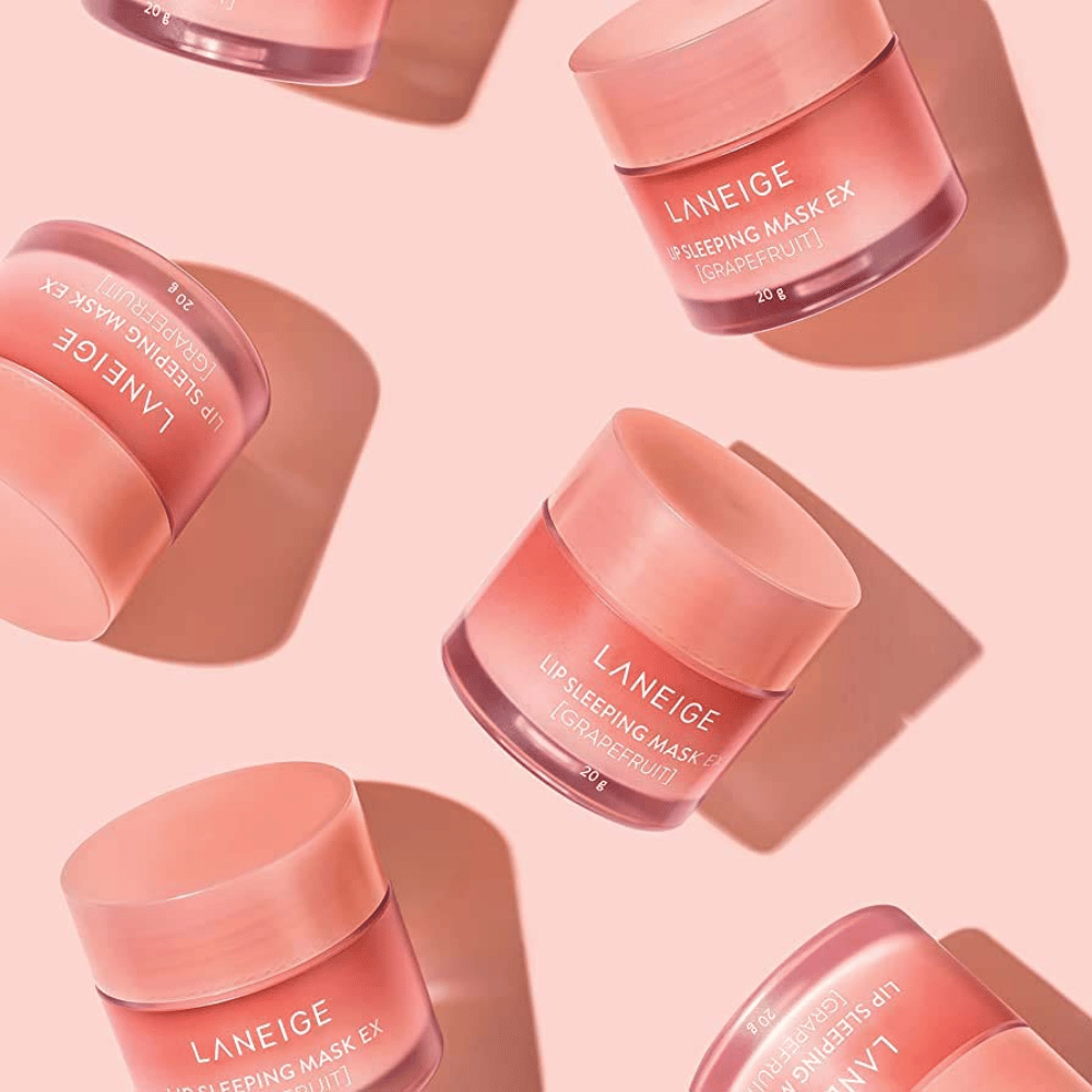 Fyra burkar LANEIGE Lip Sleeping Mask Grapefrukt 20g på rosa bakgrund, främjar grapefrukt och återfuktning.