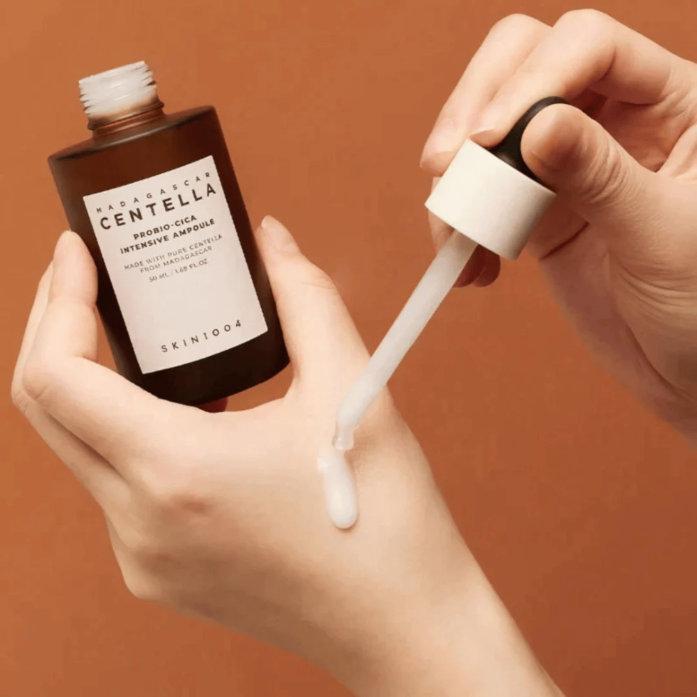 Händer som använder dropppipett för att dosera "Madagascar Centella Probio-Cica Intensive Ampoule" från SKIN1004.