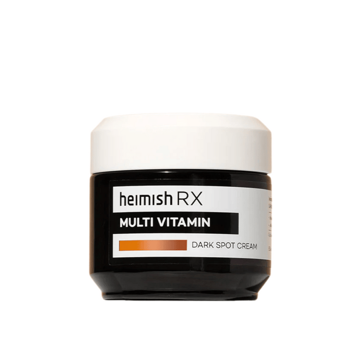 Heimish RX Multi Vitamin Dark Spot Cream i en stilren svart burk med vit lock. En ansiktskräm berikad med multivitaminer, framtagen för att reducera mörka fläckar och jämna ut hudtonen.